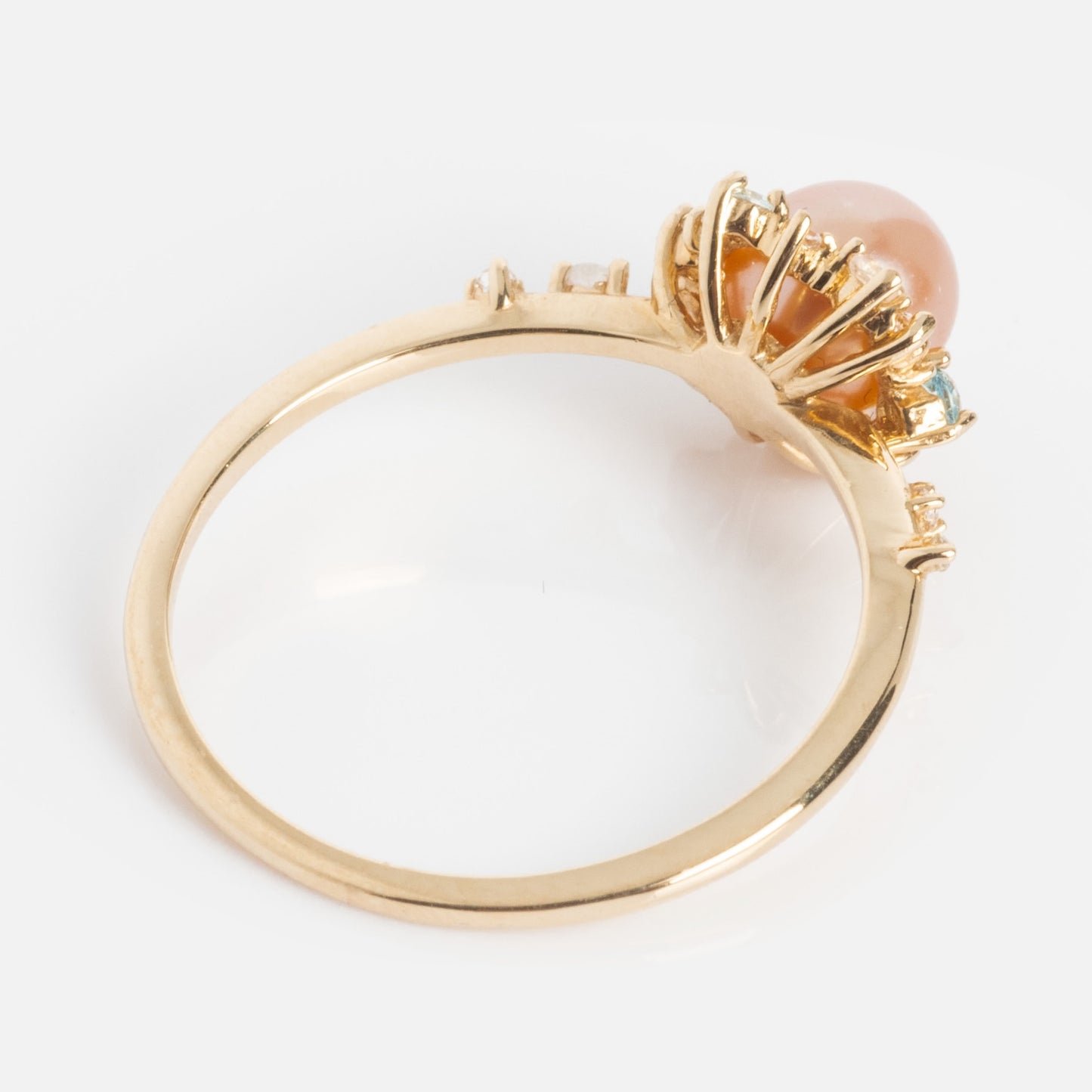 The 14k Pastel Pink Pearl Statement Ring features a round pastel pink pearl in a raised prong setting, accented by sparkling clear stones, making it stand out beautifully against a white background.
