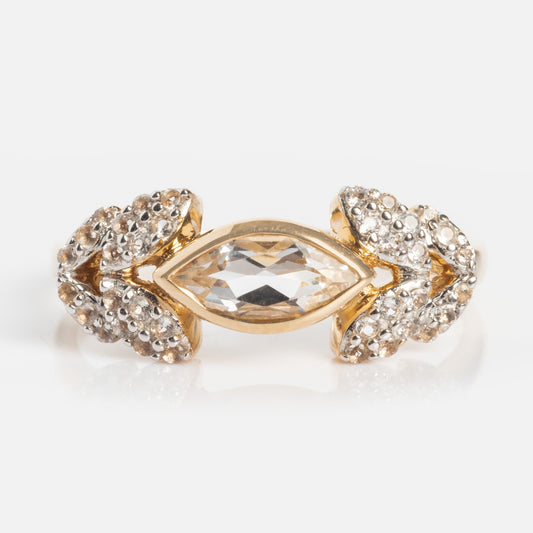 The 14k Vintage Inspired Laurel Crown Ring features a marquise-cut clear center gemstone, accented by clusters of small round stones on each side in an ornate, symmetrical gold design.
