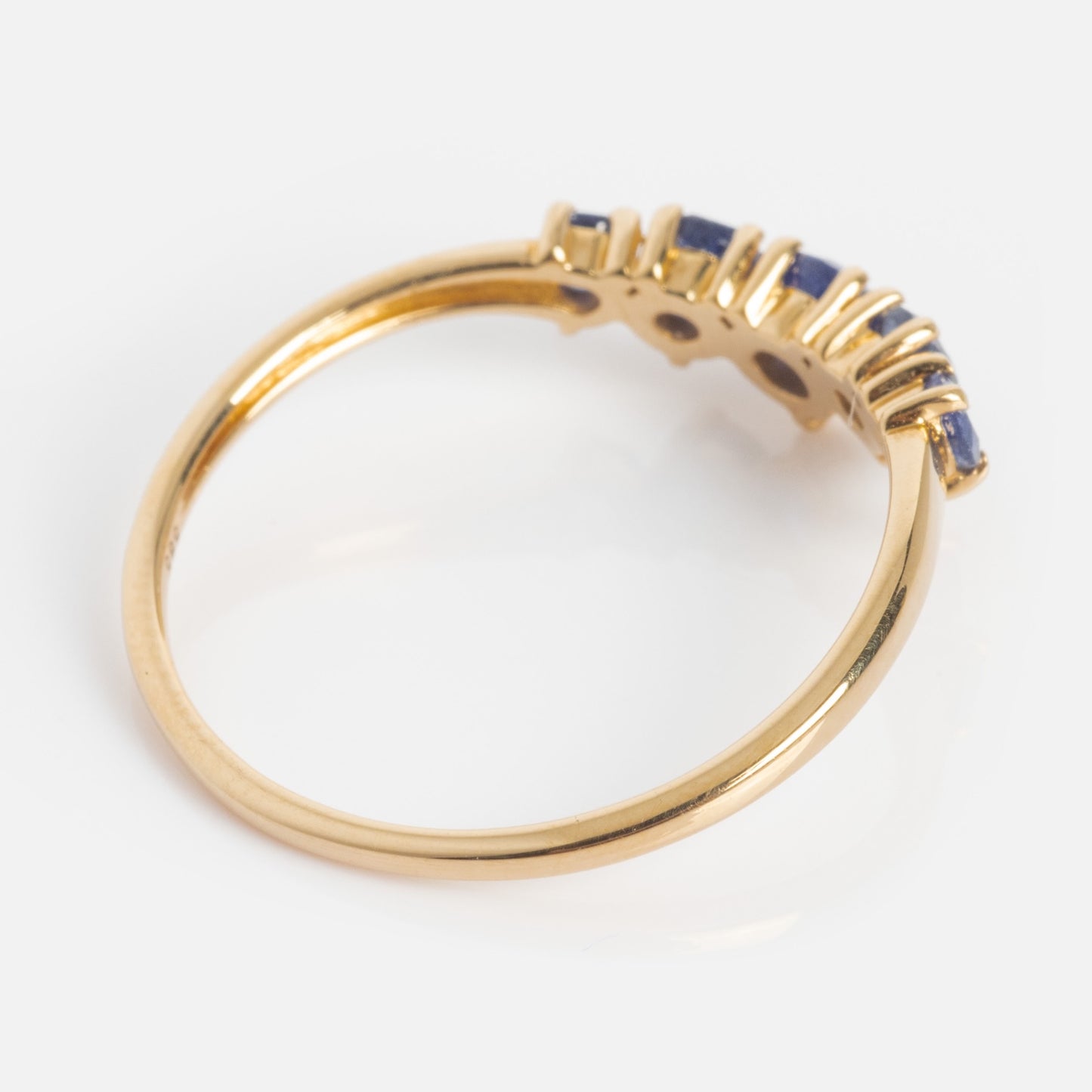 The 14k Blue Sapphire Arc Nesting Ring features a thin yellow gold band with five small prong-set blue sapphires arranged in a row on the upper half, displayed against a plain white background.
