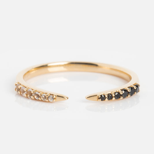 The 14k Black and White Open Front Nesting Band features a delicate 14k gold band with small white stones on one end and black stones on the other, displayed on a plain surface against a white background.