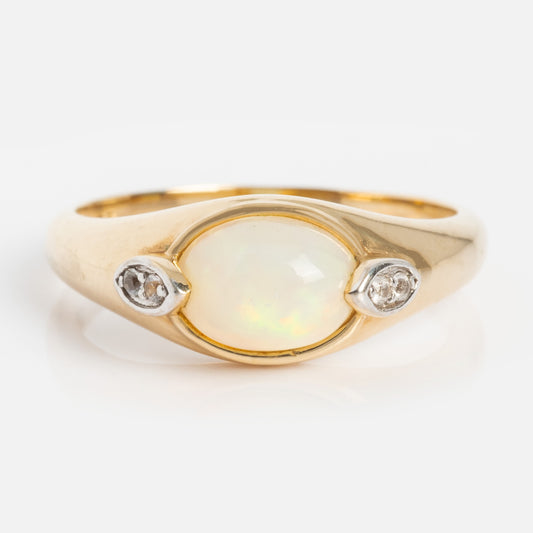 The Solid Gold Crystal Ball Opal Ring features an oval Ethiopian opal center stone flanked by two small round diamonds, set against a plain white background.