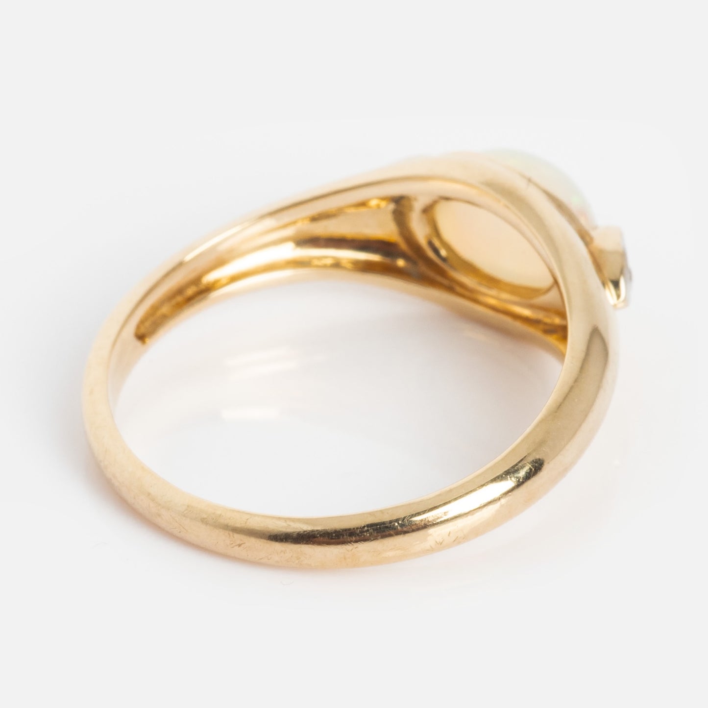 A close-up of the Solid Gold Crystal Ball Opal Ring with a smooth band is shown from the side and slightly underneath, highlighting its light-colored Ethiopian Opal gemstone setting against a plain white background.