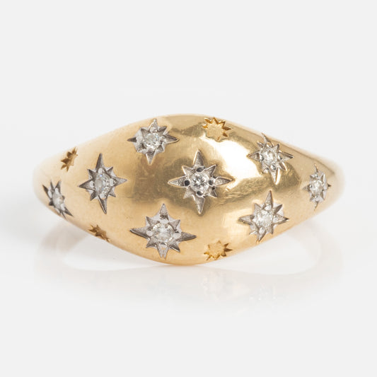 The Solid Gold Star Crossed Dome Pinky Ring features star-set diamonds nestled in star-shaped engravings, elegantly arranged across its gracefully curved band.