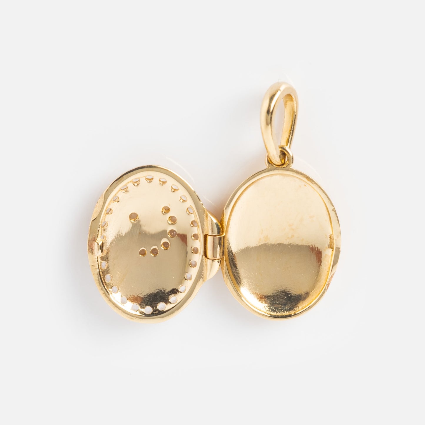 A Local Eclectic exclusive, the Solid Gold Amulet Charm is an oval locket with dotted detailing on one side and a plain, reflective surface on the other. With a small top loop, its perfect for adding to your favorite gemstone necklace.