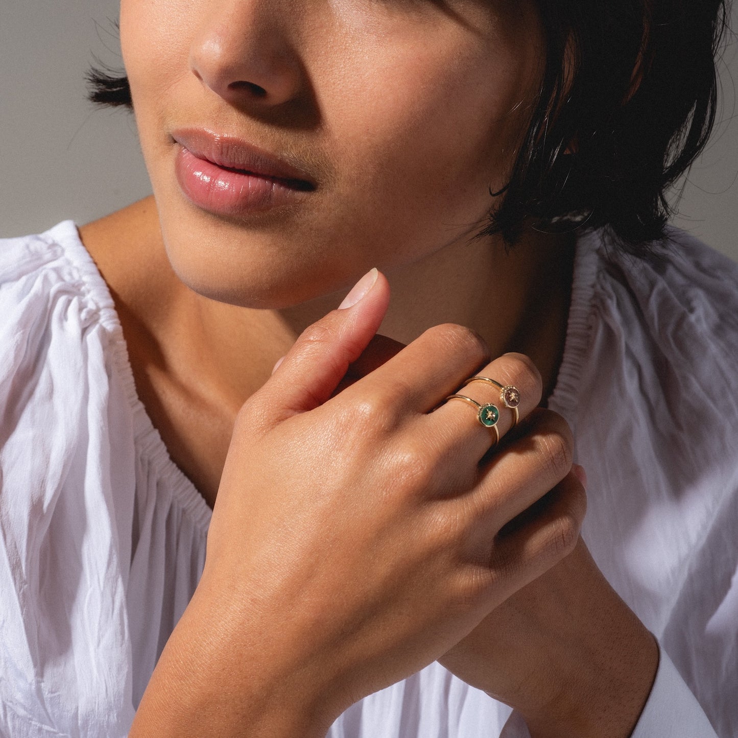 A woman in a white blouse gently clasps her hands, highlighting the Solid Gold Crystal Crescent Moon Ring for Manifestation. Her face is partly visible, with smooth skin and natural makeup.