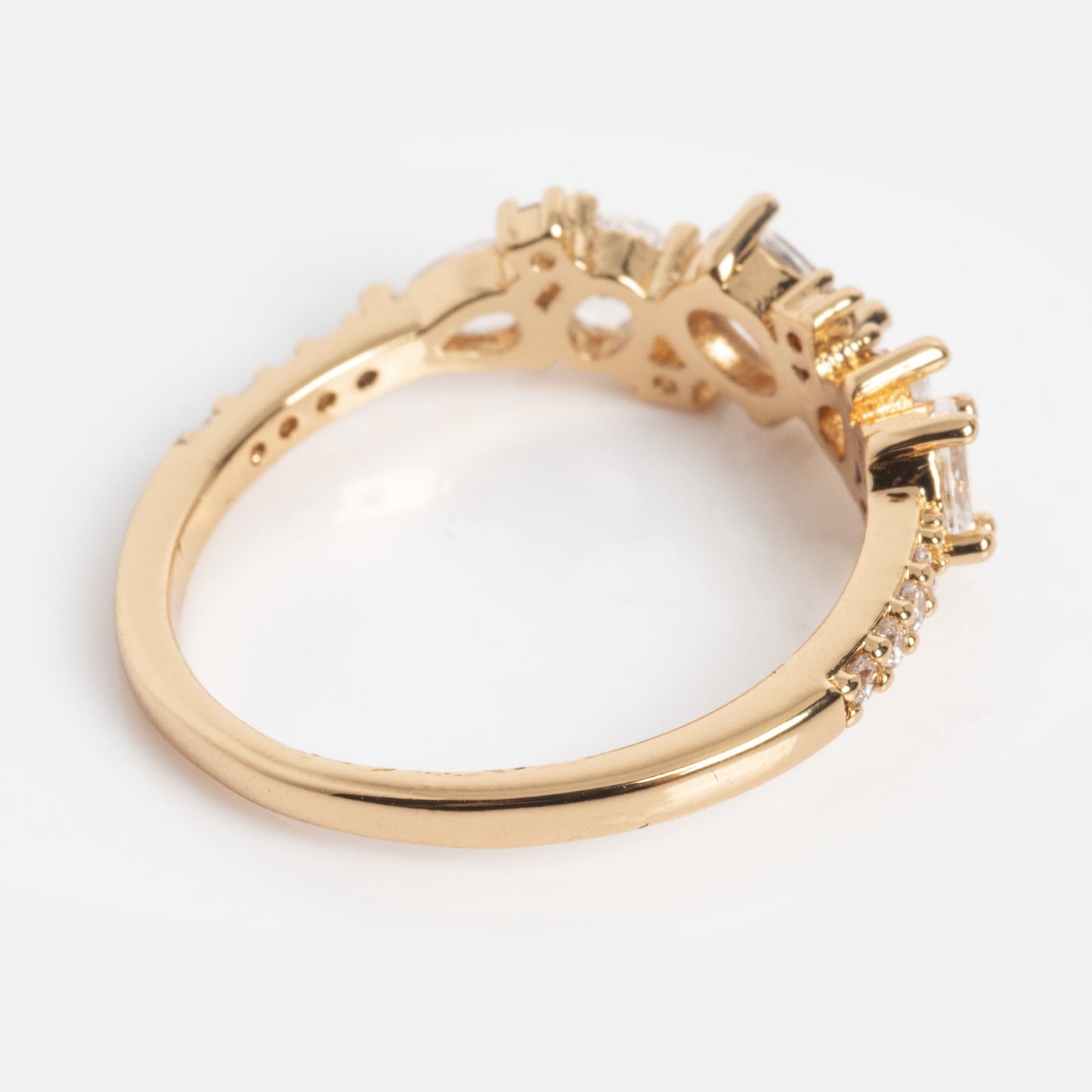 The Statement Crystal Cluster Ring showcases baguette-cut and round clear crystals set in a gold band, displayed from an angled side view against a plain white background.