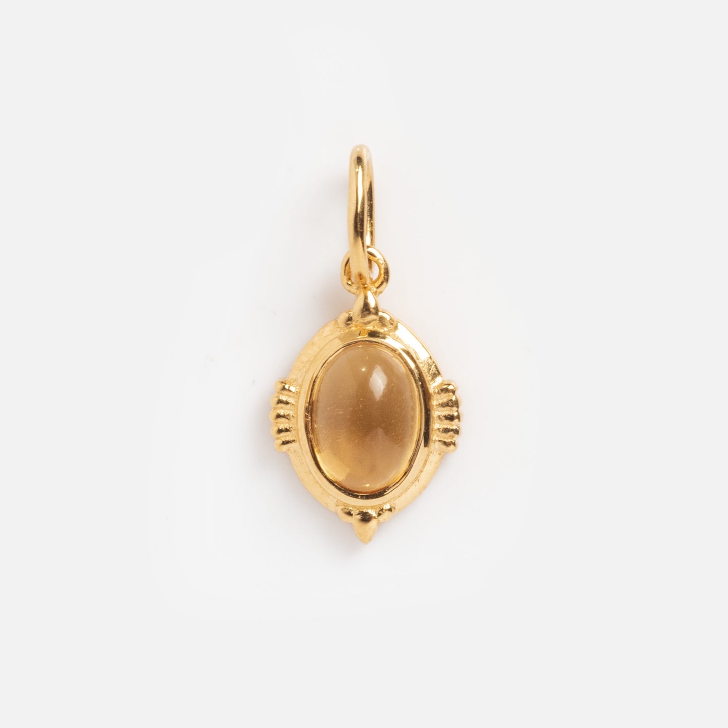 The Vintage Inspired Pendant Charm features an oval-shaped gold design with a smooth amber stone, decorative accents, and a small top loop—perfect for fans of Period Piece jewelry.