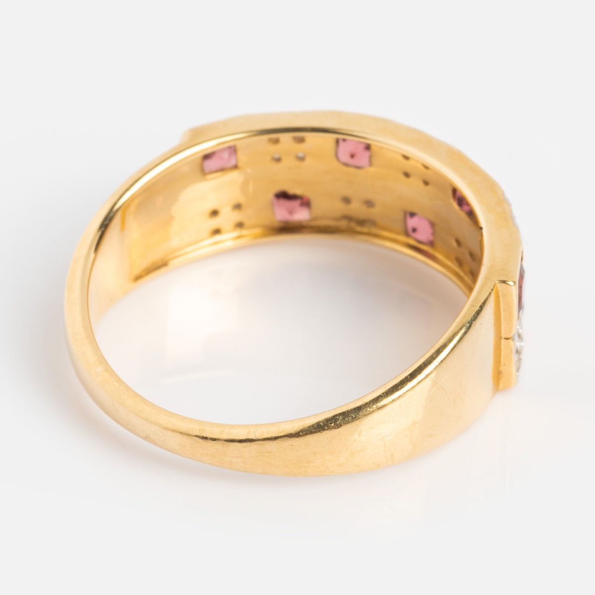 A close-up of the Family Gold Solid Gold Garnet and Topaz Checkerboard Band shows pink gemstones set inside its elegant checkerboard design, viewed from the side against a plain white background.