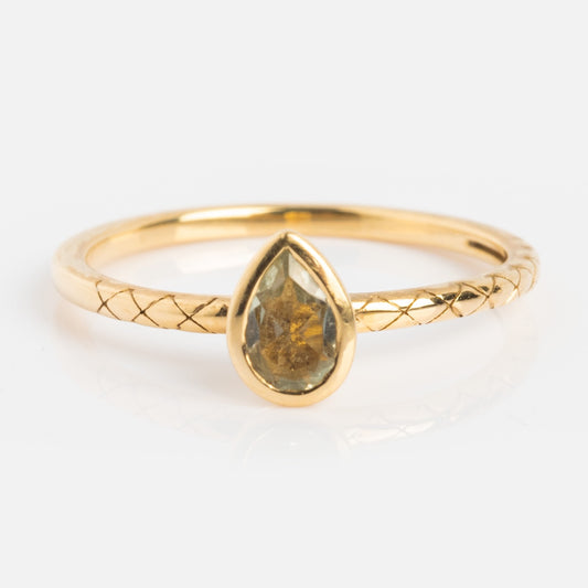 A solid gold ring with a textured band features a pear-shaped green amethyst bezel set at the center, displayed on a white background.