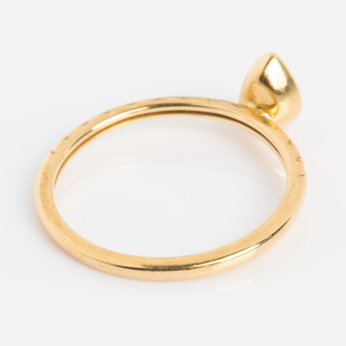 A solid gold ring featuring a smooth, pear-shaped green amethyst accent, displayed against a plain white background.