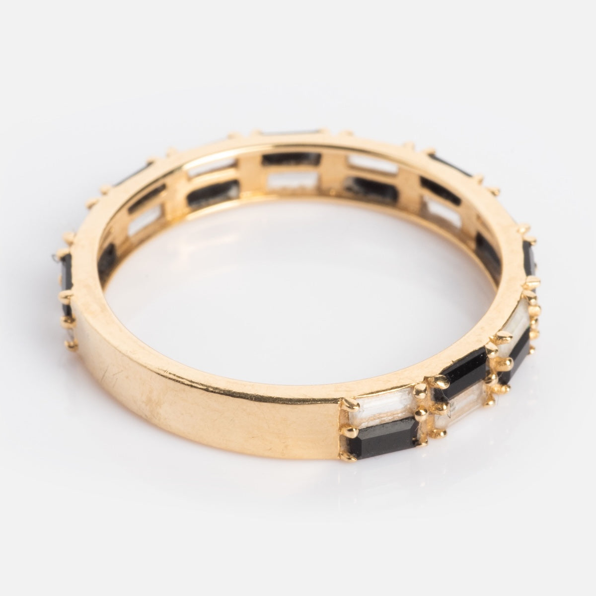 The Solid Gold Black and White Checkerboard Band features alternating rectangular black agate and white stones set in solid gold, shown encircling the ring against a white background.