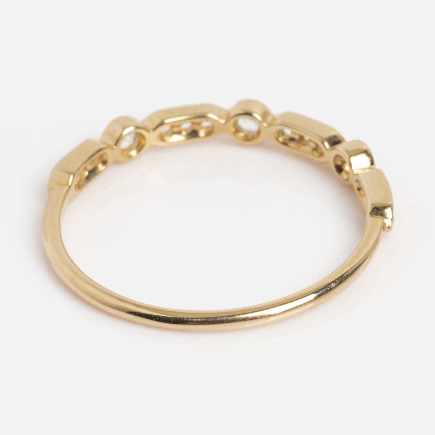 The Solid Gold Bezeled Shimmer Stacking Ring features a smooth gold band in front and small rectangular chain links at the back, beautifully displayed on a plain white background.