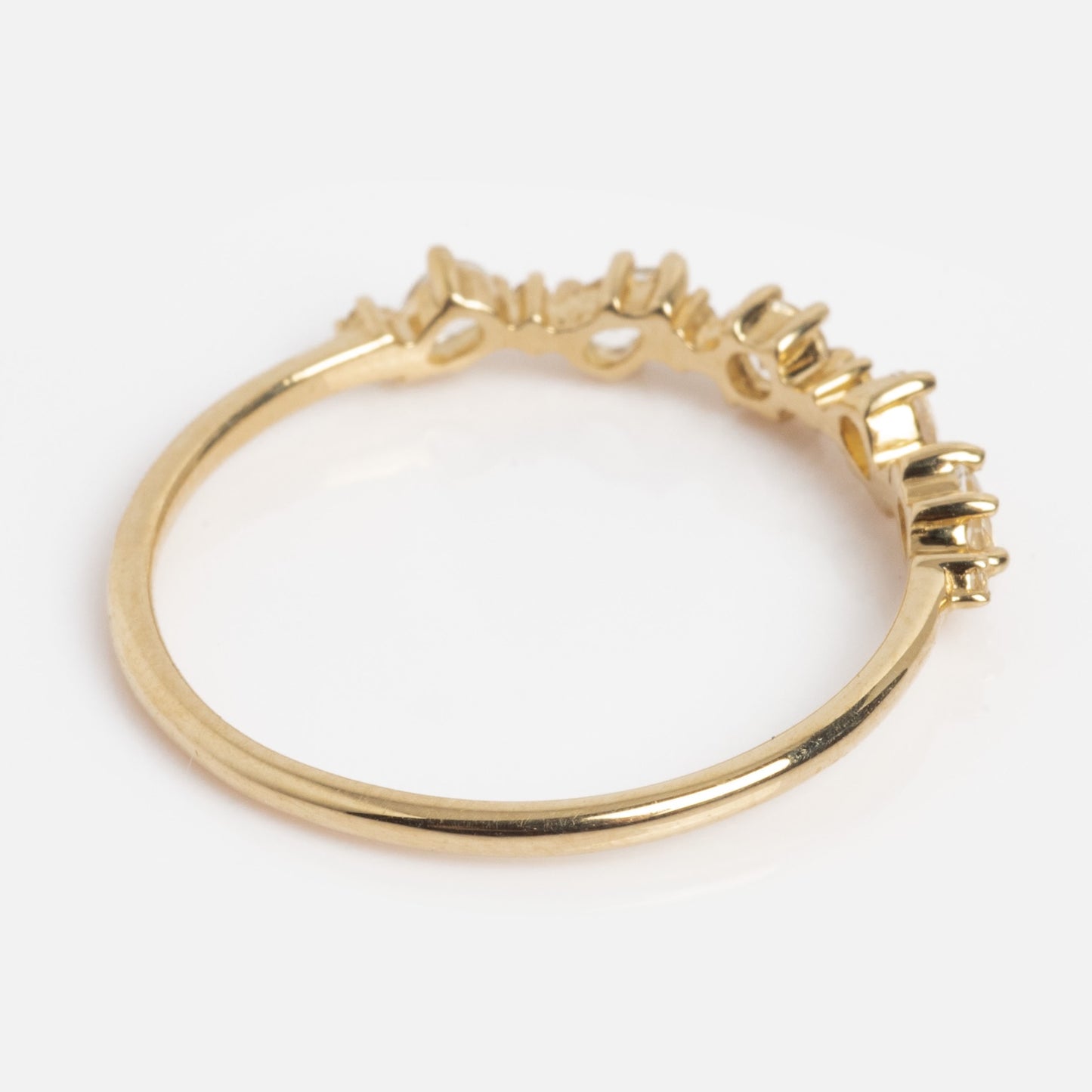 The Solid Gold Floating Gems Stacking Ring features an irregular, textured design along the top edge and is shown on a plain white background.