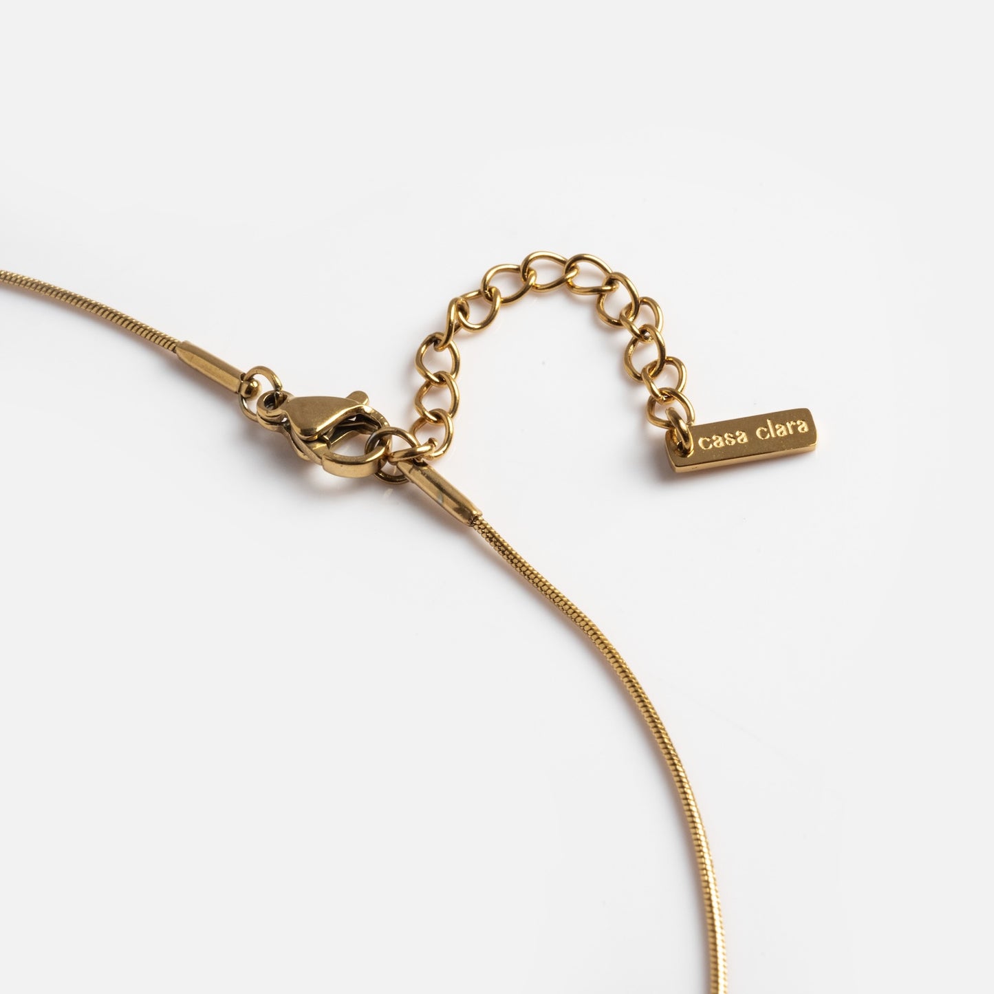 Close-up of the Yellow Necklace with a lobster clasp, extension chain, and a rectangular tag engraved with casa clara at the end. The necklace is shown on a white background.
