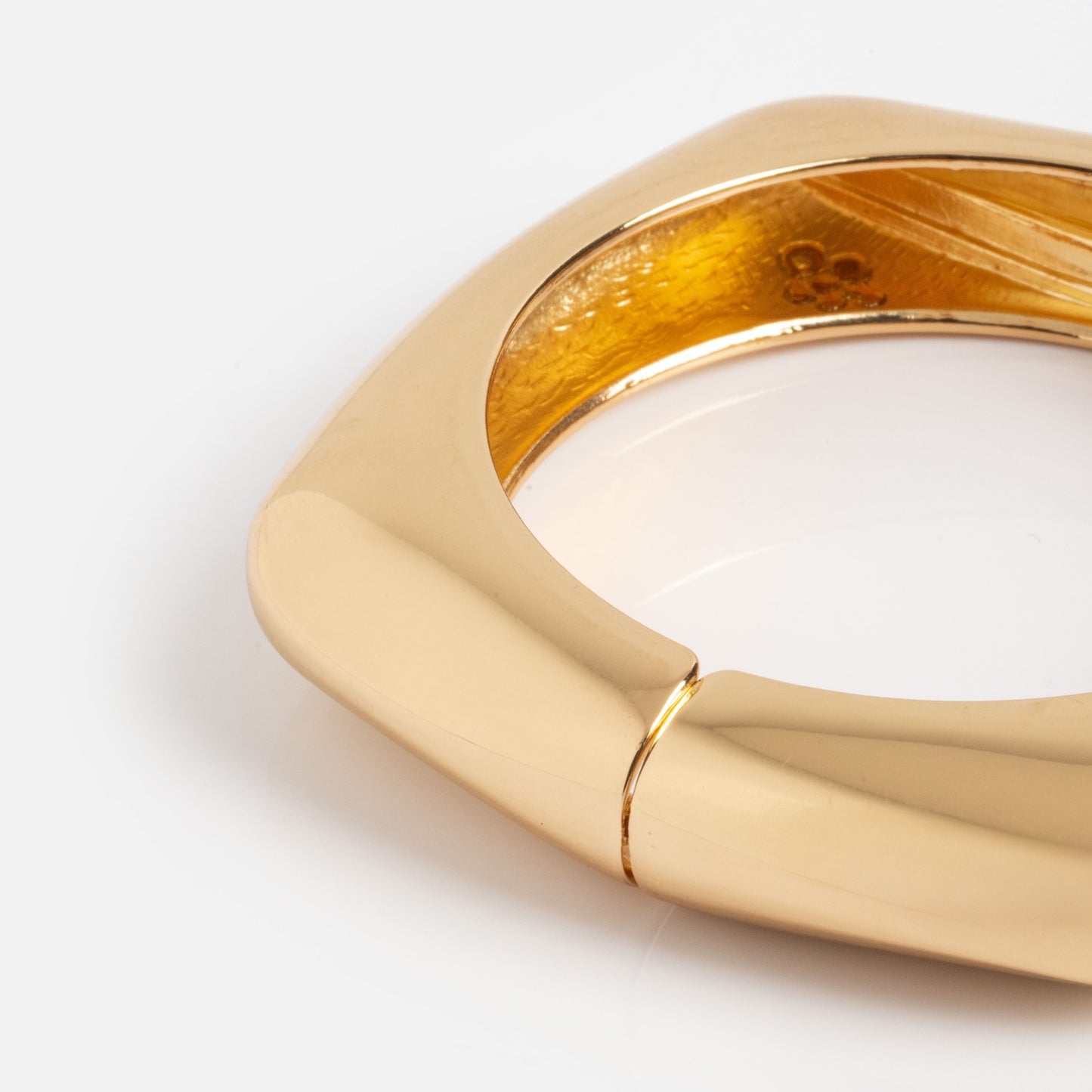 Close-up of the Square Cuff Bracelet, featuring a chunky, geometric gold design with a smooth, shiny finish and hinged clasp, displayed against a plain white background.