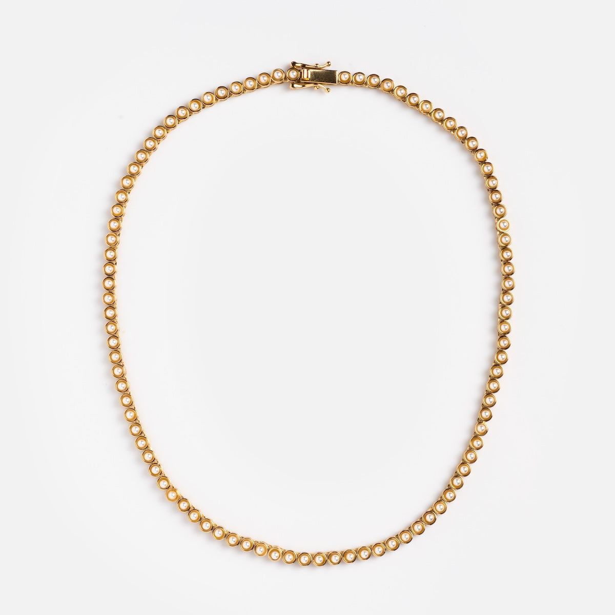 The Tennis Necklace in Pearl is crafted in 14k yellow gold, featuring evenly spaced round beads on a single strand with a clasp, shown against a plain white background.