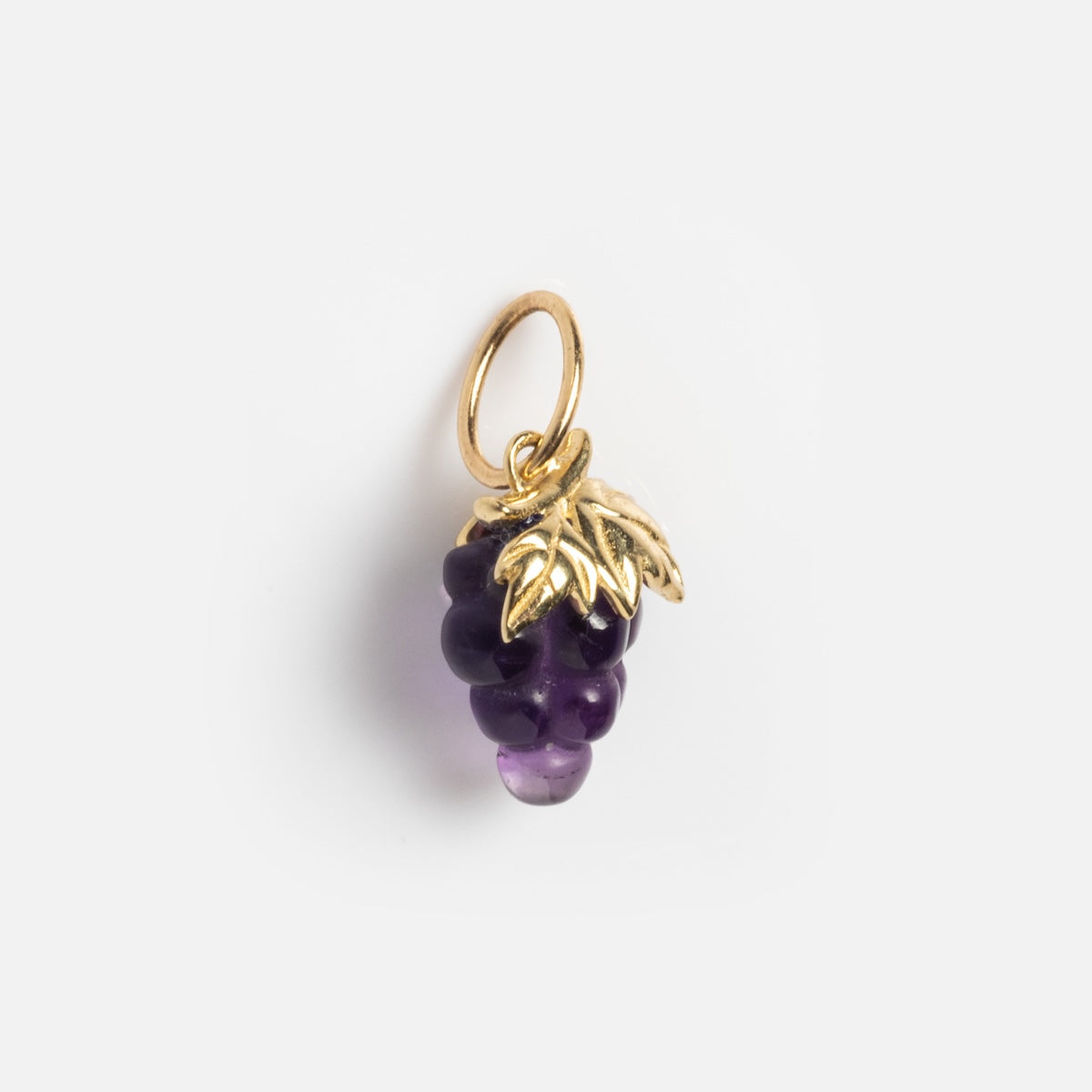 The Solid Gold Foodie Charm is a 9k yellow gold necklace shaped like a grape bunch, with purple beads as grapes and a gold leaf on top, all attached to a gold loop.