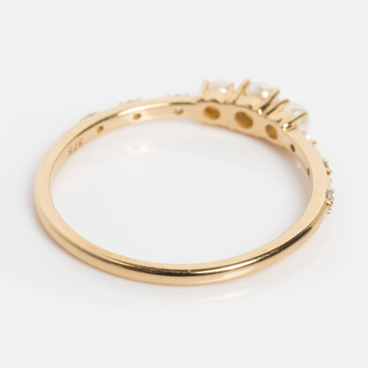 A close-up of the Solid Gold Luminous Pearl Trio Ring, featuring three luminous pearls set on one side, shown from an angled perspective against a plain white background.