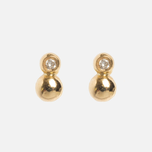 Solid Gold Diamond Dawn Ball Studs: a pair of solid gold earrings featuring a small round diamond set above a larger gold sphere, shown on a plain white background.