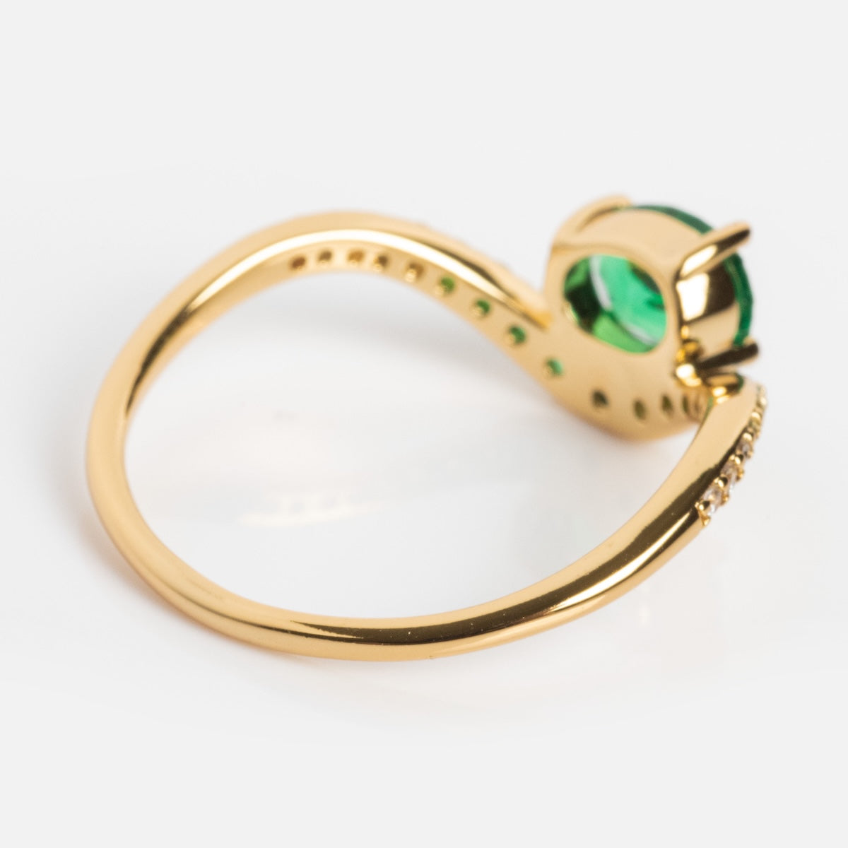 The Main Character Floating Ombre Birthstone Ring features a gold wavy band with a round green gemstone in a prong setting and small accent stones lining one side. A unique birthstone jewelry piece, shown on a plain white background.
