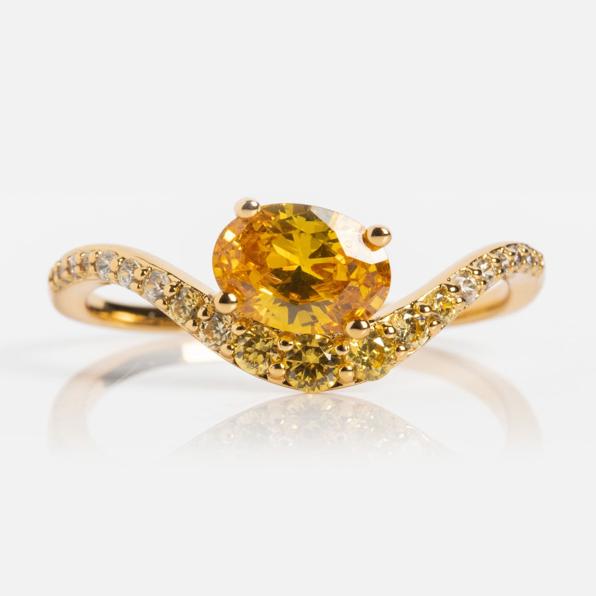 The Main Character Floating Ombre Birthstone Ring showcases a large round yellow gemstone at the center, accented by a wavy band adorned with smaller clear and yellow stones for an elegant ombre effect.