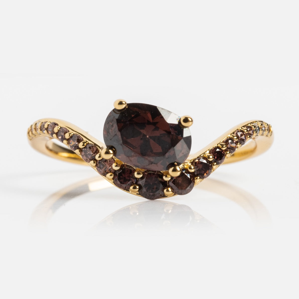 The Main Character Floating Ombre Birthstone Ring showcases a large, round dark red center stone with smaller matching gems elegantly set along a curved wave band in a gold ombre finish.