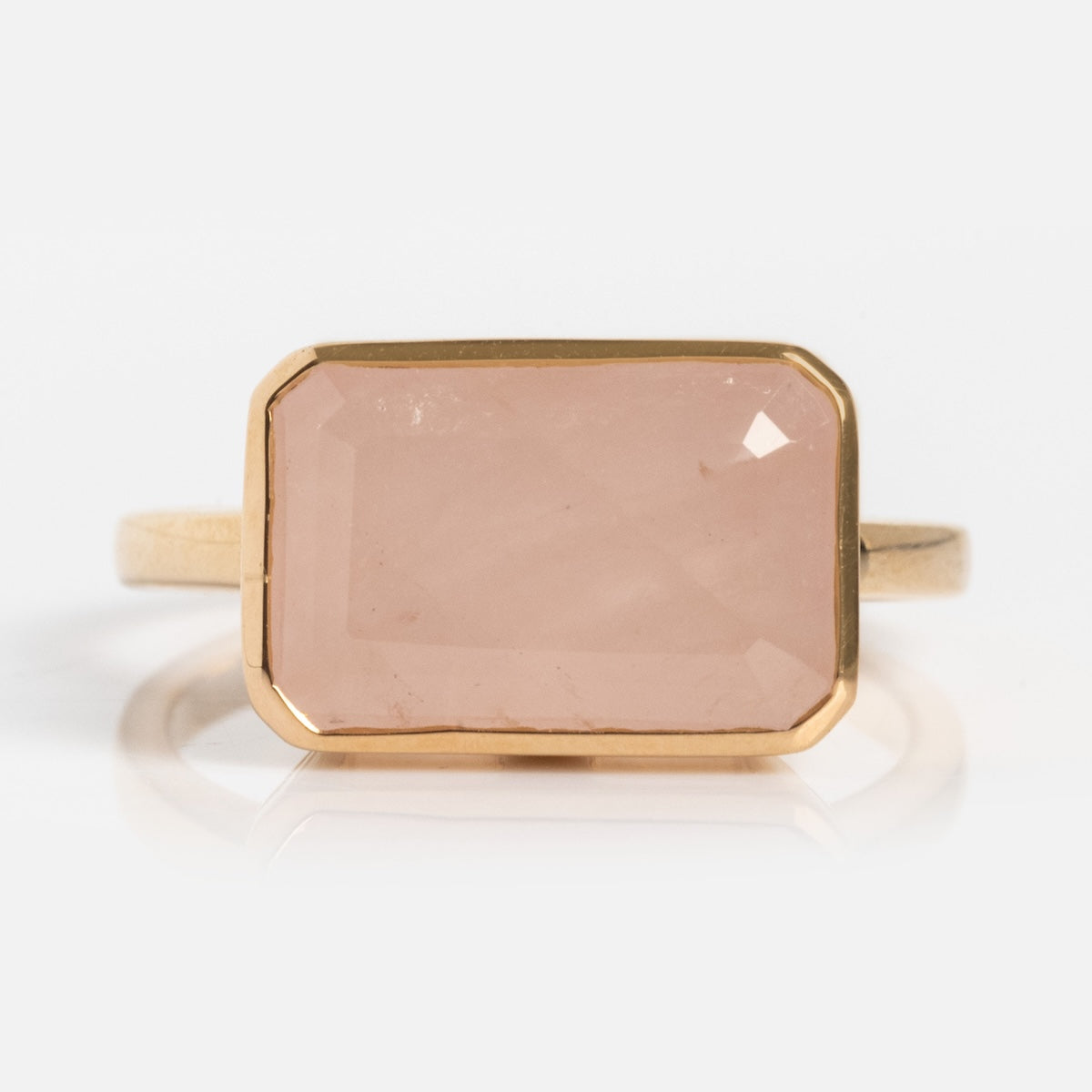 A modern heirloom, the 14k Jojo Ring is crafted from solid yellow gold and showcases a large, rectangular faceted rose quartz gemstone in a simple bezel setting on a plain white background.