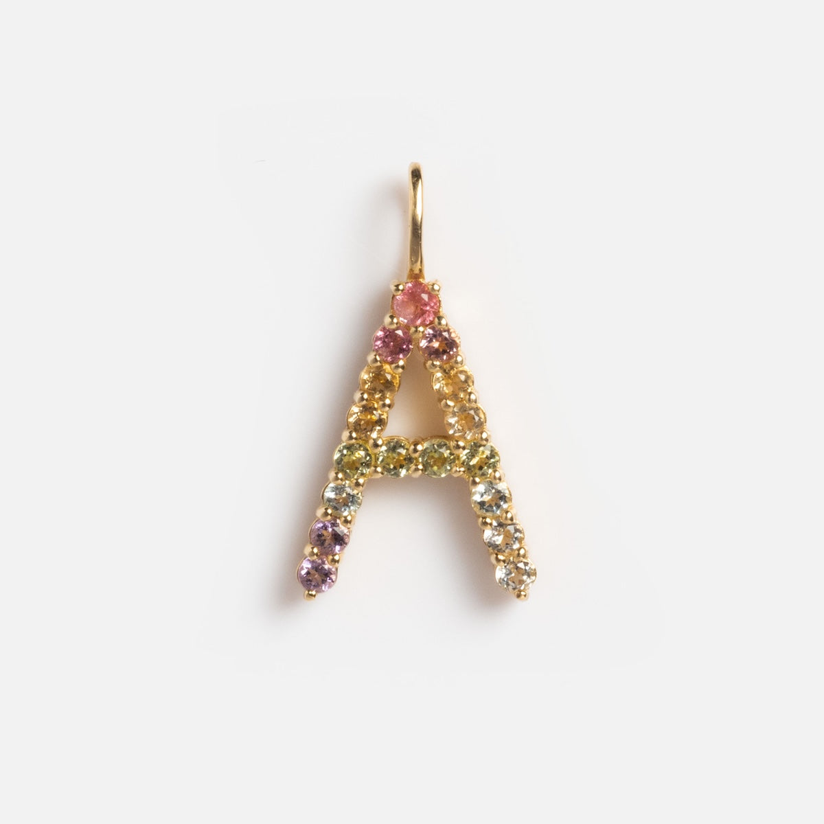 The Solid Gold Pastel Gemstone Letter Charm Sample is a 9k yellow gold “A” pendant, accented with small, multicolored gemstones like pink tourmaline, shown on a plain white background.