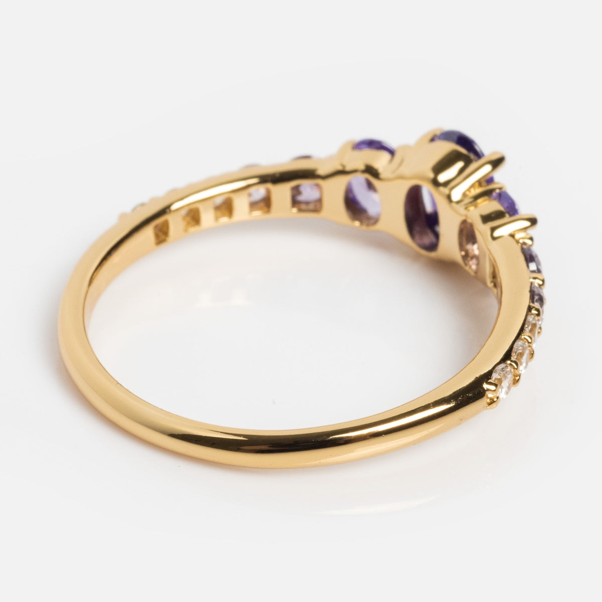 The True Colors Classic Ombre Birthstone Ring features 14k gold plating, a row of small clear stones on the band, and two oval purple gemstones set side by side in prongs, shown against a white background.