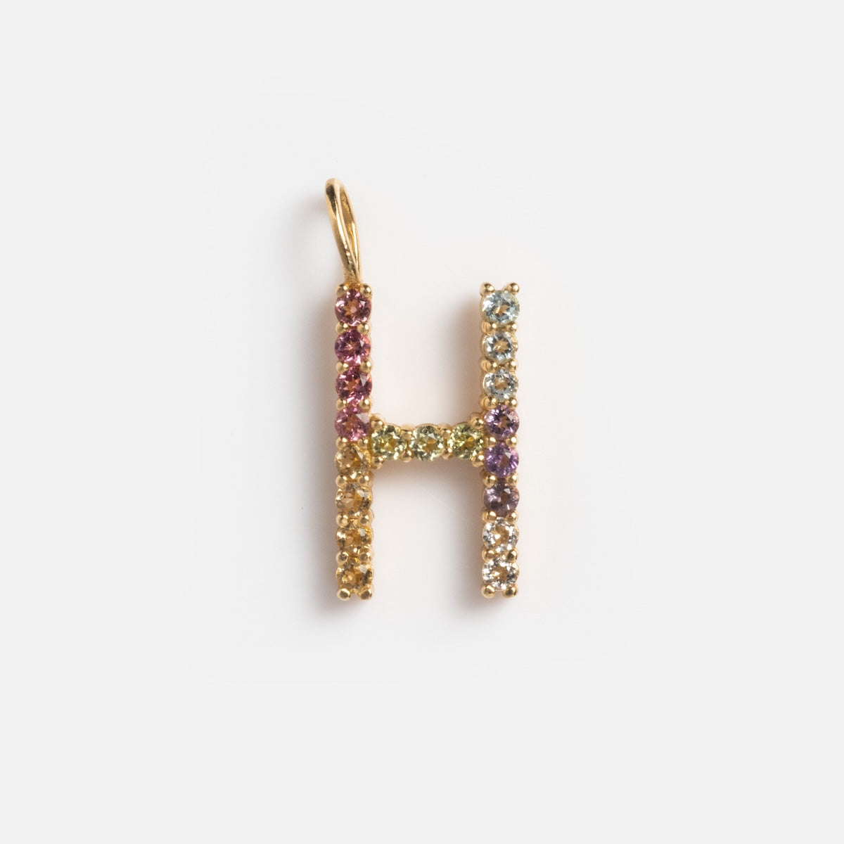 The Solid Gold Pastel Gemstone Letter Charm Sample is a 9k yellow gold H-shaped pendant adorned with pastel gemstones in shades of purple, green, blue, yellow, and pink tourmaline.
