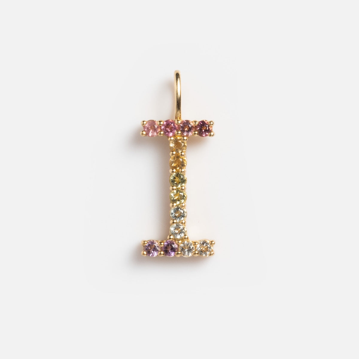 The Solid Gold Pastel Gemstone Letter Charm Sample is a 9k yellow gold pendant shaped like the letter I, adorned with pink tourmaline and other multicolored gemstones, shown on a plain white background.