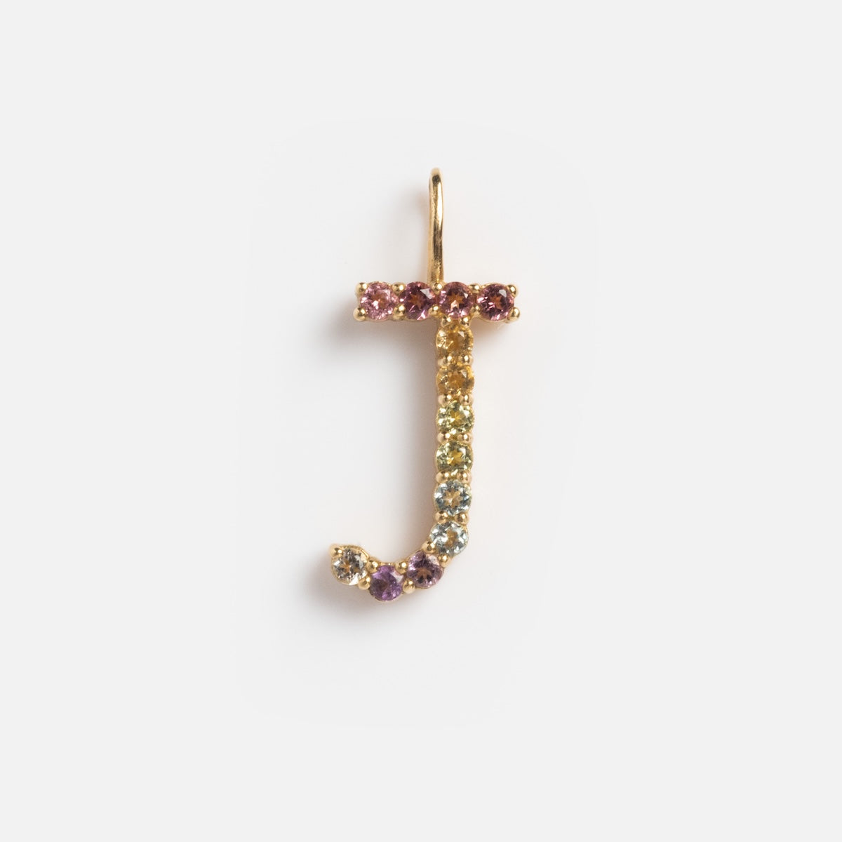 The Solid Gold Pastel Gemstone Letter Charm Sample is a 9k yellow gold J-shaped pendant featuring small, colorful gemstones like pink tourmaline, shown against a plain white background.