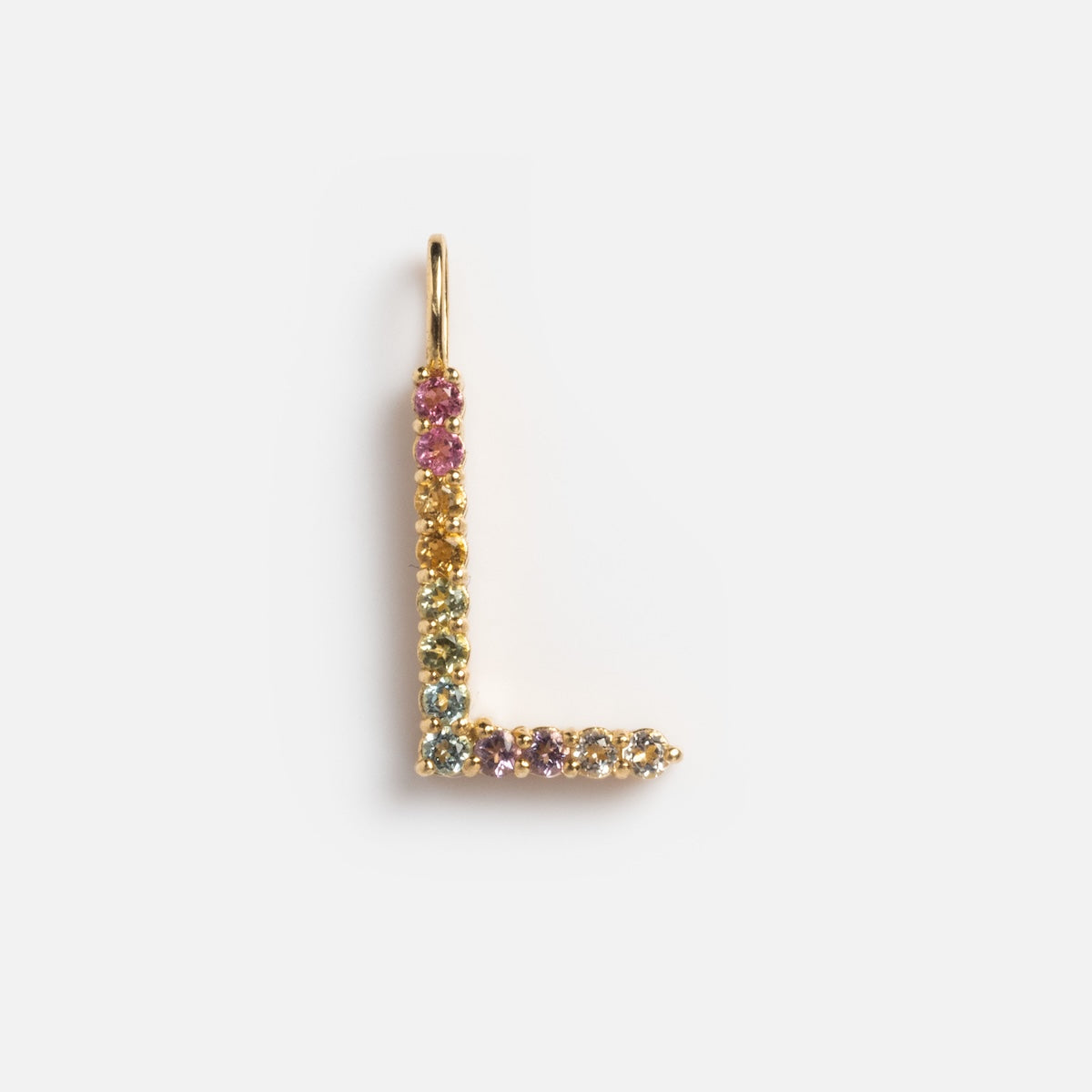 The Solid Gold Pastel Gemstone Letter Charm Sample is a 9k yellow gold L-shaped pendant, featuring small, colorful gemstones like pink tourmaline in a gradient design, displayed on a white background.