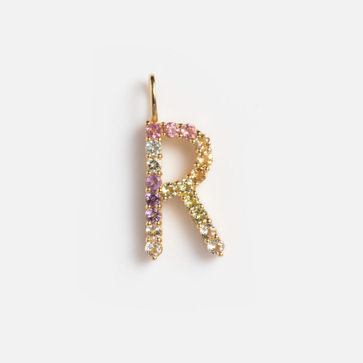 The Solid Gold Pastel Gemstone Letter Charm Sample features a 9k yellow gold R pendant adorned with pink tourmaline, purple, green, and clear pastel gemstones, creating a vibrant look against a white background.