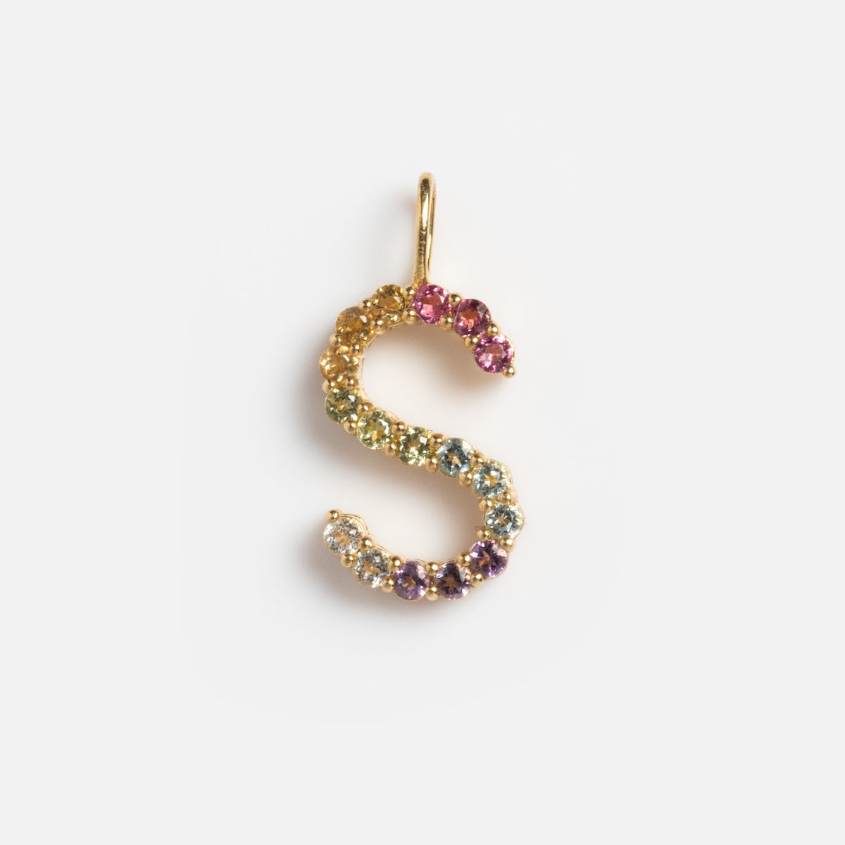 The Solid Gold Pastel Gemstone Letter Charm Sample is an S-shaped pendant in 9k yellow gold, set with pastel multicolored gemstones like pink tourmaline, shown on a plain white background.