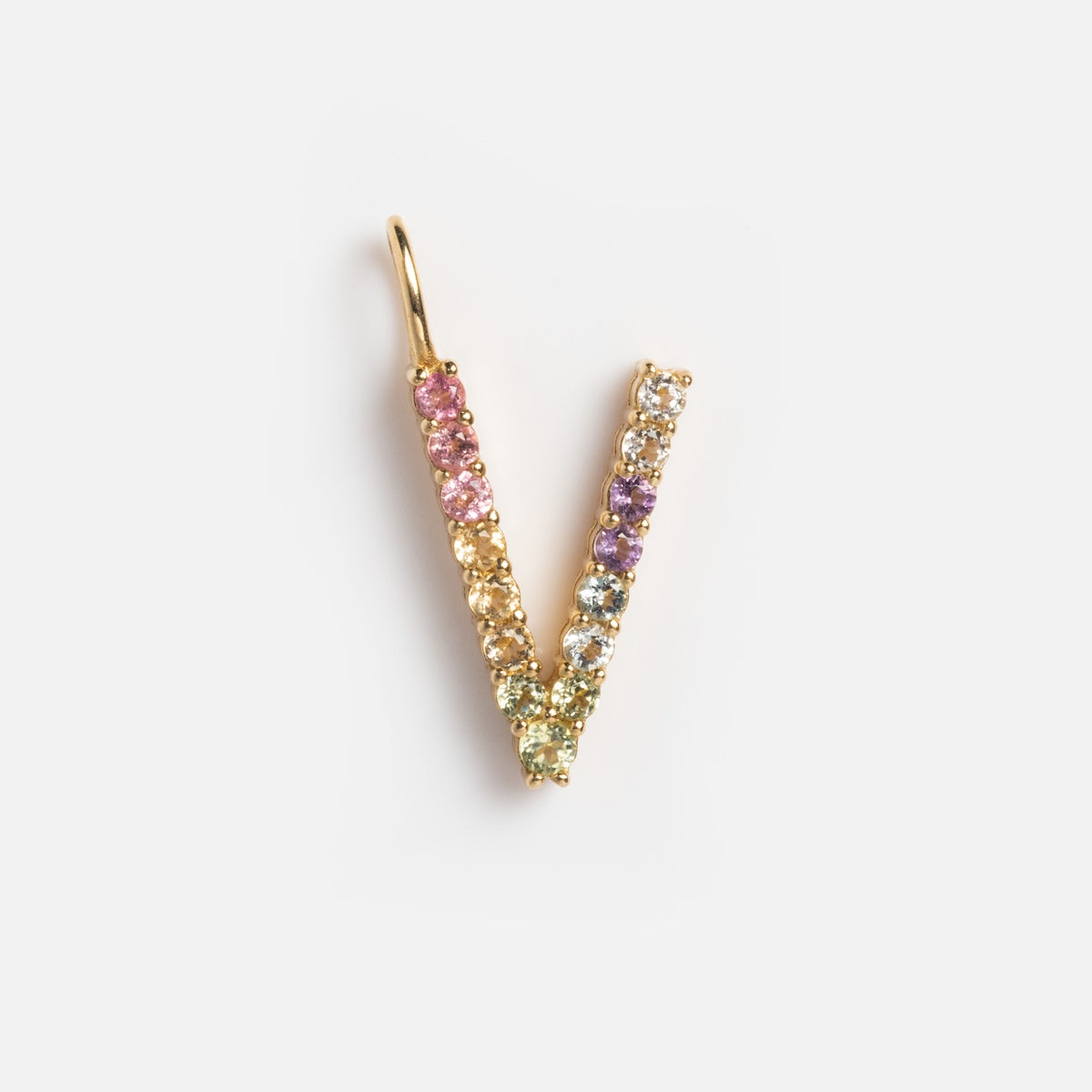 The Solid Gold Pastel Gemstone Letter Charm Sample, shaped like a V and adorned with multicolored gemstones in a gradient pattern featuring pink tourmaline, shines against a plain white background.