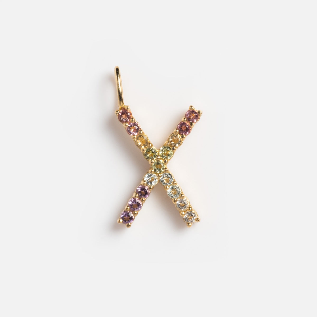 The Solid Gold Pastel Gemstone Letter Charm Sample is a 9k yellow gold X pendant, embellished with small pastel multicolored gemstones, shown against a plain white background.