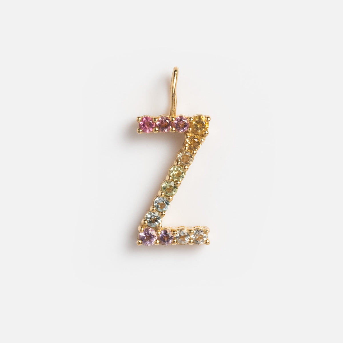 The Solid Gold Pastel Gemstone Letter Charm Sample features a 9k yellow gold Z-shaped pendant adorned with small, multicolored gemstones including pink tourmaline, shown on a plain white background.