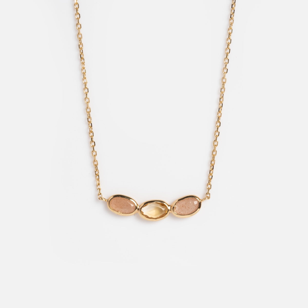 The Solid Gold Morning Light Citrine and Sunstone Necklace by Local Eclectic features three small oval stones—citrine and sunstone—in gold settings, displayed side by side on a plain white background.