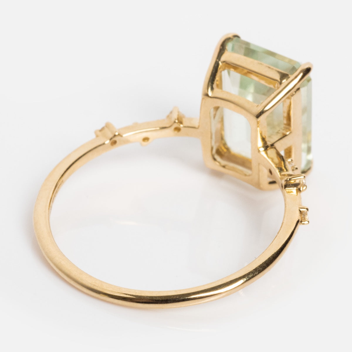The Solid Gold Dewdrop Green Amethyst Statement Ring features a large, rectangular green amethyst in a raised prong setting, with an angled view highlighting the side and band against a white background.