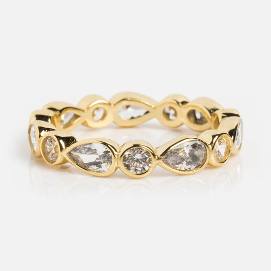 The Isla Ring is an elegant everyday band by Melinda Maria, crafted in CZ 18k yellow gold with alternating pear-shaped and round clear gemstones in a continuous pattern, displayed on a plain white background.