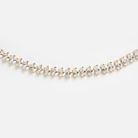 A close-up of the Hello Gorgeous Tennis Necklace, featuring 18k gold plating and a row of round, sparkling simulated diamonds set closely together against a plain white background.