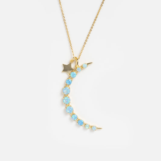 The What Dreams Are Made of Blue Opal Necklace features a gold plated crescent moon adorned with iridescent blue opal stones and a tiny gold star charm, displayed on a white background.