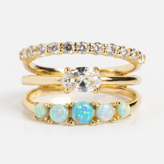 The Shes So Stacked Ring features three gold plated bands: the top with simulated diamonds, the middle a bold simulated diamond design, and the bottom accented with three round simulated opal stones.