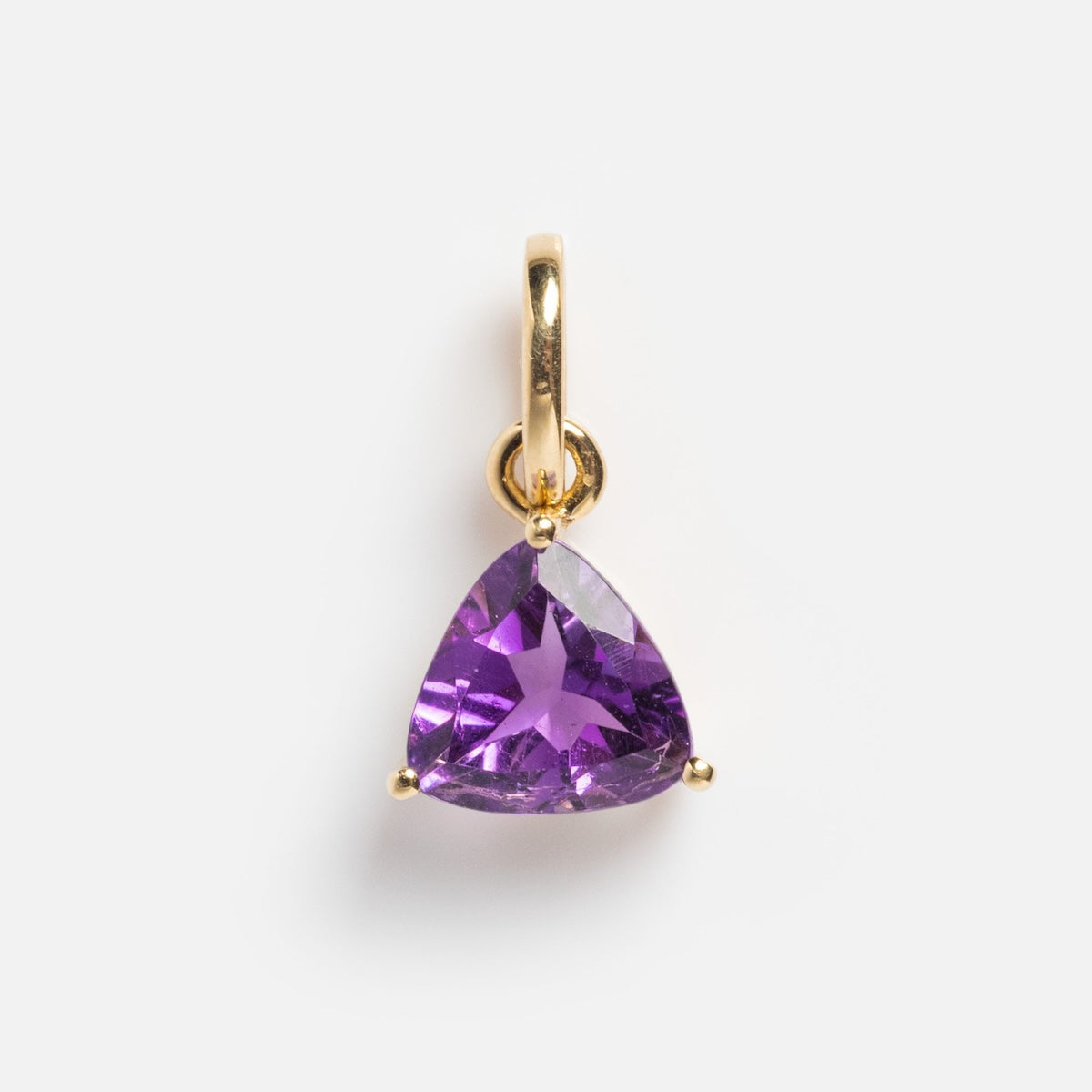 The Solid Gold Trillion Birthstone Charm features a trillion cut amethyst set in 9k yellow gold with three prongs, shown against a plain white background.