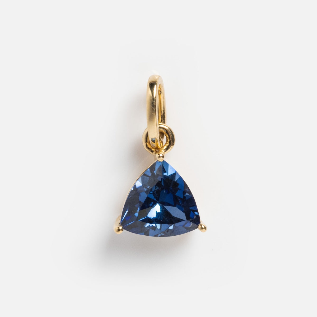 The Solid Gold Trillion Birthstone Charm features a trillion-cut blue gemstone in a three-prong setting, crafted from 9k yellow gold, and photographed against a plain white background.