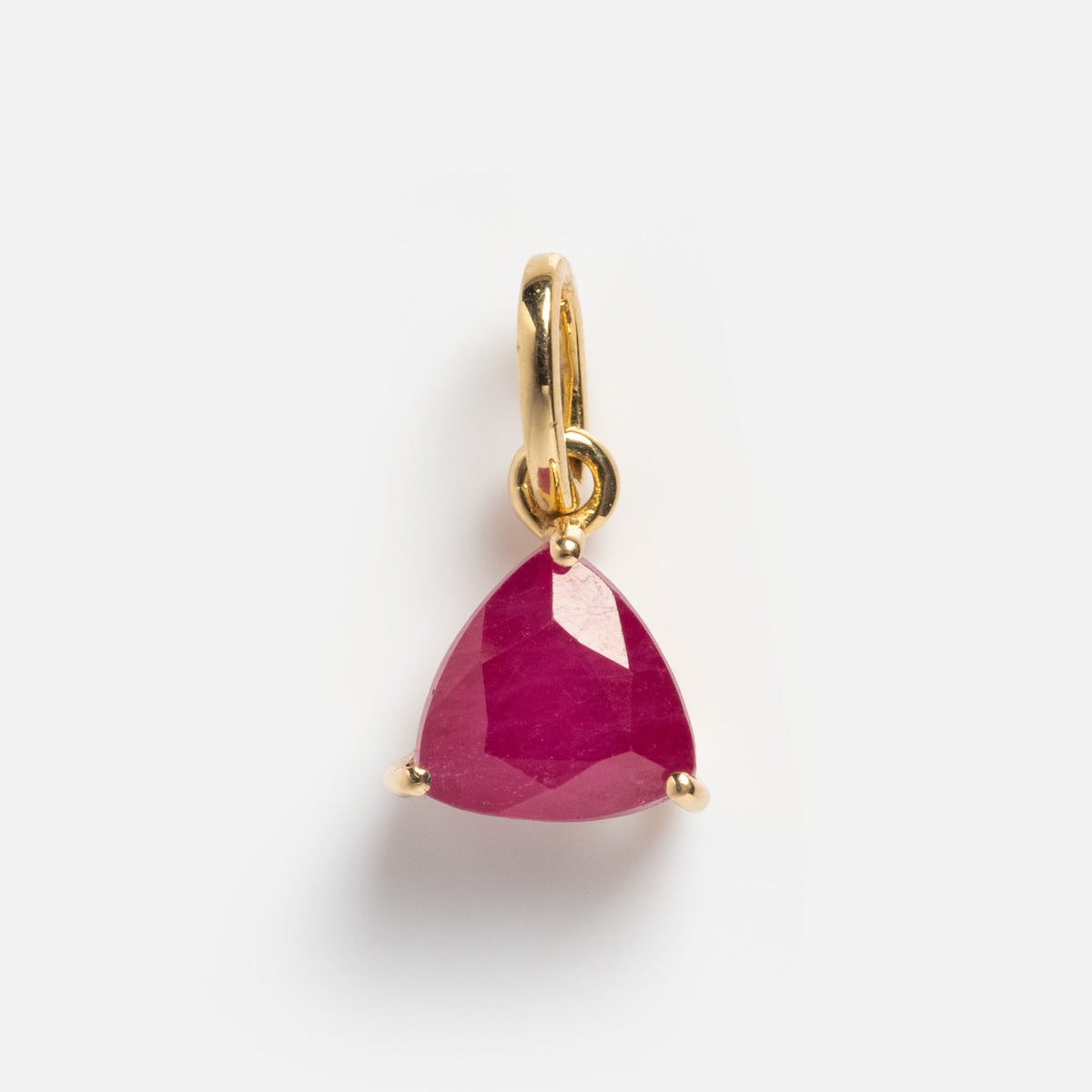 The Solid Gold Trillion Birthstone Charm is crafted in 9k yellow gold, showcasing a faceted trillion-cut deep pink birthstone set in a three-prong setting on a plain white background.