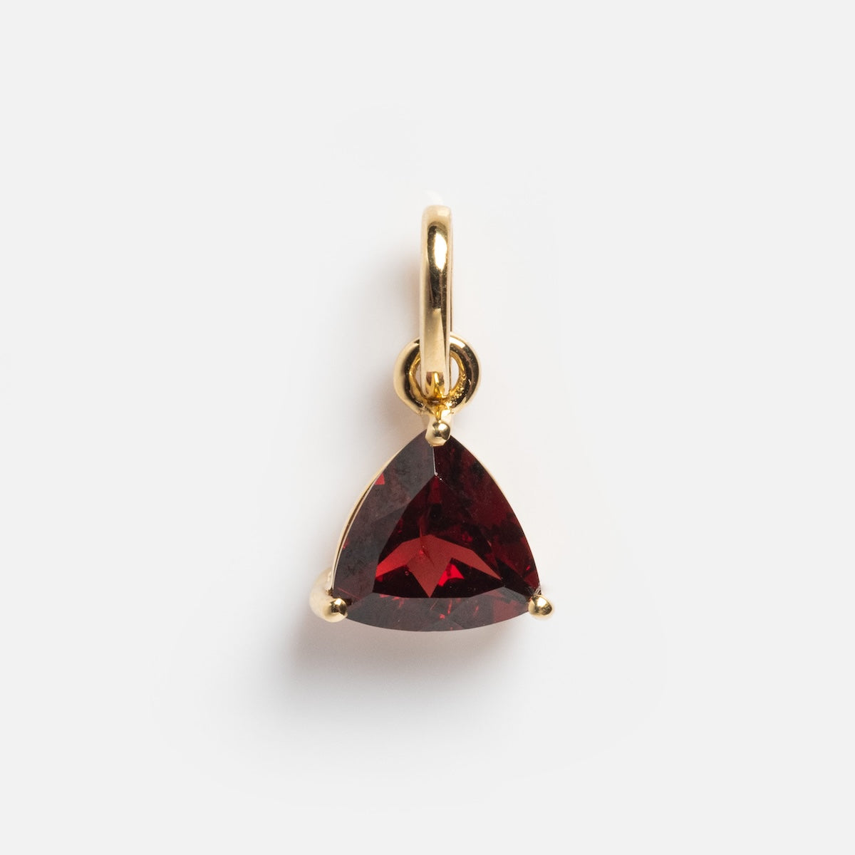 The Solid Gold Trillion Birthstone Charm features a deep red trillion-cut stone set in a small 9k yellow gold loop, shown on a plain white background.