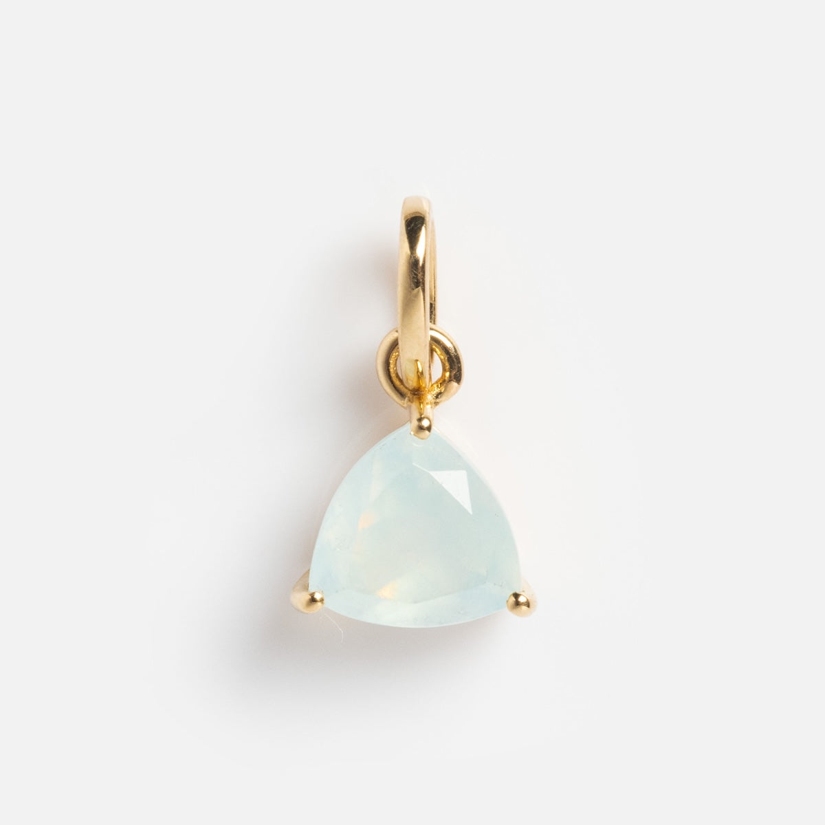 The Family Gold Solid Gold Trillion Birthstone Charm features a pale, translucent trillion-cut stone in a three-prong setting, shown against a plain white background.