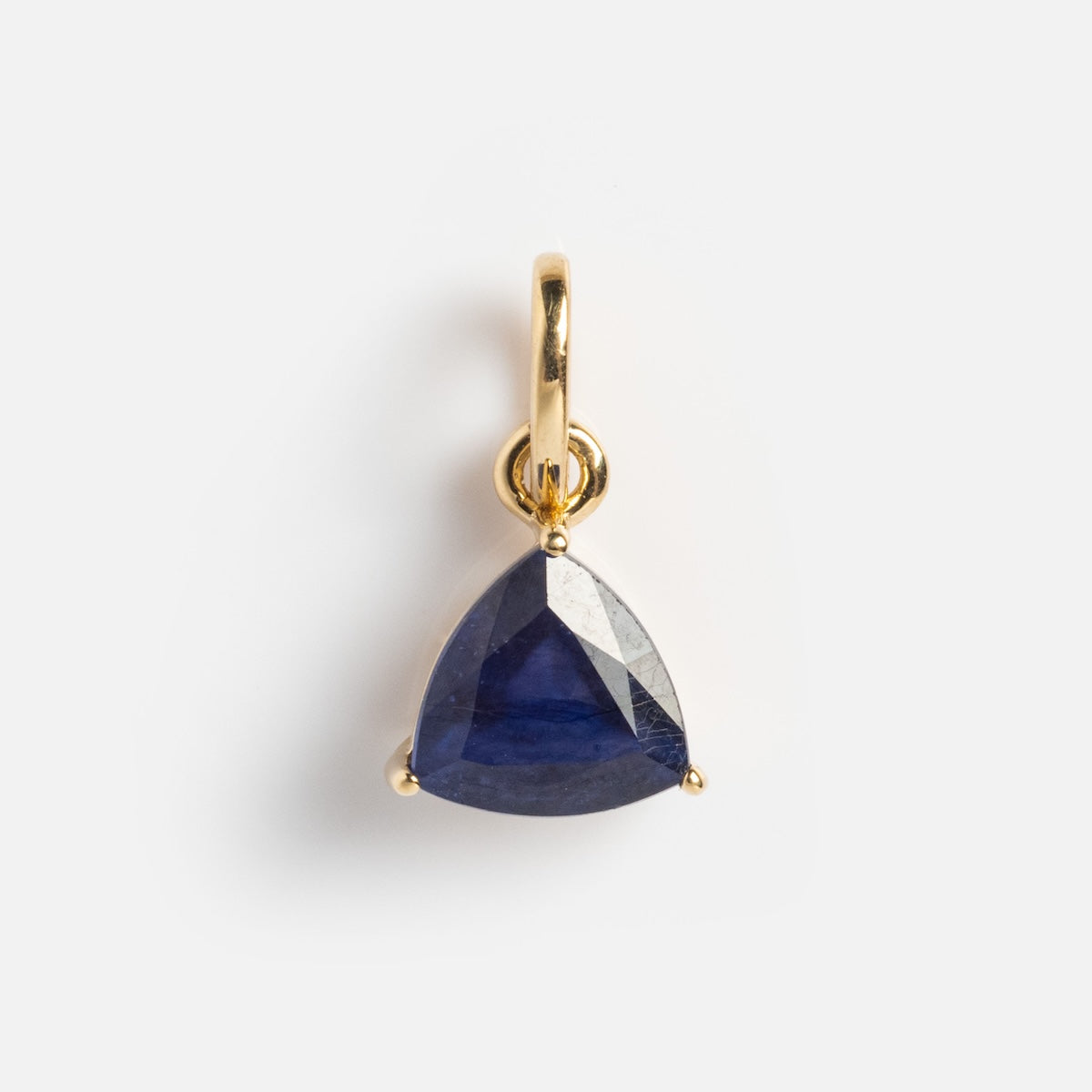 A close-up of the Solid Gold Trillion Birthstone Charm, showcasing a blue trillion-cut gem set in 9k yellow gold.